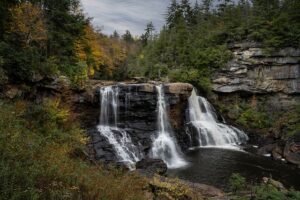 waterfalls and steep cliffs in a forest on a cloudy day