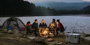 people around a campfire at a lake in the woods
