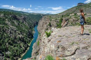 women standing on a ledge above a canyon with river 