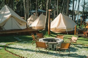 tents near the woods and a fire pit with chairs