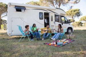 people sitting in chairs at a picnic with a camper