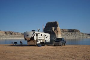  person sitting in a chair with a camper and a truck at a lake