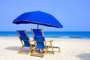 Sandy beach with a colorful umbrella set up next to the ocean waves.