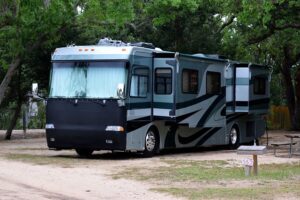 Camper in the woods on a dirt road with trees