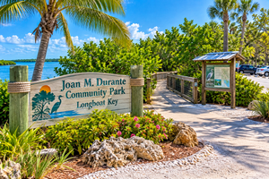 Longboat Key: Tranquil Beaches & Upscale Charm on Florida’s Gulf Coast 15 Scenic illustrated entrance to Joan M. Durante Community Park on Longboat Key, Florida, featuring a wooden park sign, mangrove boardwalk, tropical palm trees, colorful flowers, and peaceful coastal waters.
