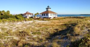 Gasparilla Island (Boca Grande): Historic Charm & Gorgeous Beaches 1 Two small beach cottages near the ocean, surrounded by grass, trees, and coastal scenery.