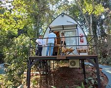 Iguazú Falls, Argentina & Brazil: Glamping Near One of the World’s Greatest Waterfalls 3 People at a glamping structure with chairs next to a concrete path in a rainforest.