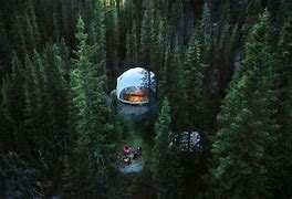 Glamping structure in a forest with people around a campfire.