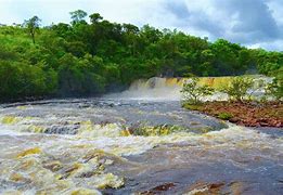 Waterfalls at a rainforest with cloudy skies and a river
