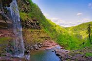 Waterfalls with steep walls and trees with vegetation on a partly cloudy day