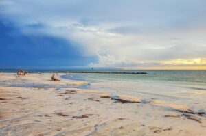 🌞🌊⛱️🐚Florida’s Most Beautiful Islands: 15 Must-Visit Gulf Coast & Keys Destinations🤿🌴 2 People on a sandy beach at the ocean on a partly cloudy day.