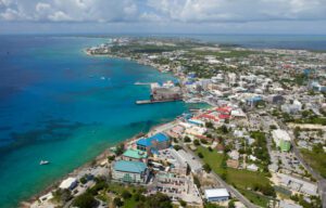 Grand Cayman: Walls, Wrecks & Wonders — Cayman Islands 1 Town with several houses and trees and grass near the ocean on a cloudy day.