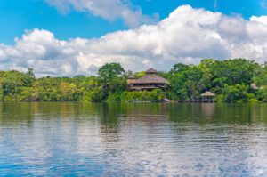 Glamping hut in a rainforest and the river on a partly cloudy day.
