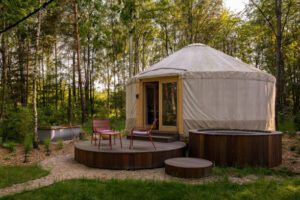 Glamping In South America: Nature Meets Comfort 1 glamping tent with chairs on a platform in the forest.