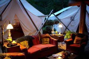 Glamping tents with couches, lights and dinner tables