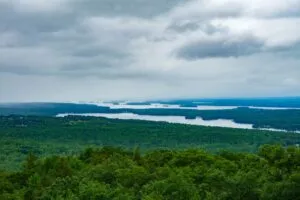 Harriman State Park, NY: Lakes, Trails & Wilderness Just Outside NYC ✨ 1 Panoramic view of forest-covered hills and scenic lakes beneath dramatic cloudy skies at Harriman State Park, New York.