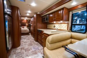 Interior of an RV camper featuring pull-out shelves, a cozy bed, and a compact dining area with natural light from the window.