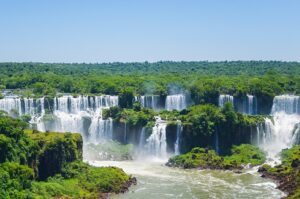 Iguazú Falls, Argentina & Brazil: Glamping Near One of the World’s Greatest Waterfalls 1 Iguazu waterfalls in a rainforest with steep wall cliffs.