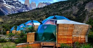 glamping dome on a structure with a wooden wall with trees and vegetation and mountains.