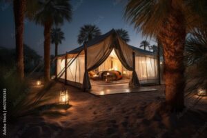 A glamping tent with a bed inside with lanterns and psalm trees