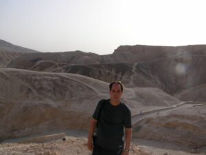 Jeffrey standing at a viewpoint with the Pyramids of Giza in the background, Egypt, under a bright blue sky.