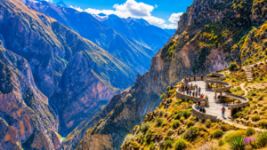 Scenic mountain viewpoint overlooking a dramatic canyon landscape in Peru, featuring a curved observation platform perched along rugged cliffs with breathtaking views of deep valleys and towering Andean peaks.