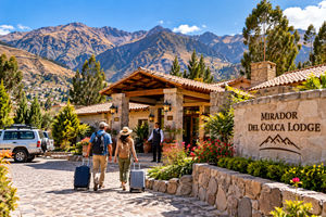 Two travelers arriving with luggage at an illustrated Mirador del Colca Lodge entrance in Chivay, Peru, featuring traditional Andean stone architecture, terracotta roofs, colorful gardens, a welcoming hotel attendant, and spectacular mountain scenery.