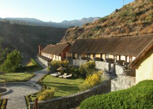 Lodge with stone walls in a canyon with mountains.