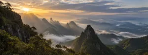 Serra Do Mar Glamping Retreat: Mountain Views And Rainforest Trails 1 Dramatic sunrise over the forested Serra do Mar mountains in Brazil, with mist drifting through deep valleys and rugged peaks.