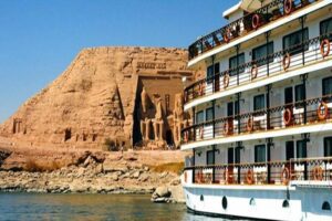 CruiseShip near ancient ruin temple on a river in the desert.