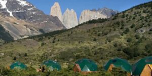Several Glasmping domes on structures with trees and vegetation and mountains.