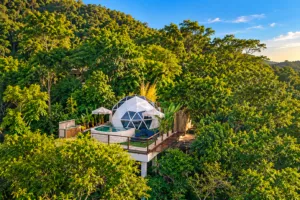 Eco Dome Retreat, Pedra Bonita – Luxury Glamping in Rio’s Rainforest 3 Geodesic glamping dome surrounded by lush tropical rainforest, featuring an elevated deck, plunge pool, lounge chairs, and secluded mountain scenery.