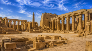 Karnak Temple – Luxor, Egypt: Gateway To Ancient Wonders 15 Wide view of Karnak Temple’s ancient courtyards and ruins in Luxor, Egypt, featuring sandstone columns, an obelisk, temple walls, and carved stone blocks.