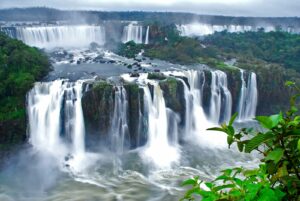 Two-tiered waterfalls cascading through lush green rainforest at Iguazu Falls.