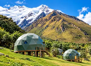 Glamping domes beneath snow-covered mountains near Ausangate, Peru, surrounded by green highland scenery and dramatic Andean peaks.