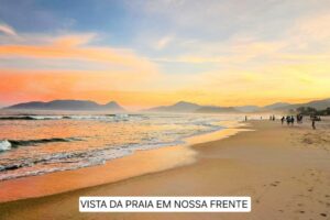 People at a Sandy beach with a glaring sun on the ocean and partly cloudy skies.
