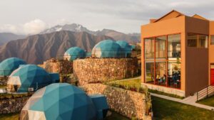 A building with six glamping domes built on stone walls, set against a backdrop of mountains.