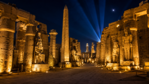 Luxor Temple – Heart Of Ancient Thebes 12 Luxor Temple illuminated at night with golden lights highlighting ancient columns, statues, hieroglyphics and the towering obelisk beneath a dark Egyptian sky.