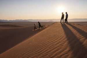 Several people walking on sand dunes during their Africa safari vacation.