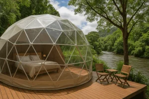 ✨ Rio De Janeiro Glamping Hub: Luxury Nature Stays in Brazil’s Most Vibrant City 23 Transparent geodesic glamping dome with a comfortable bed on a wooden deck beside a peaceful river surrounded by lush green forest.