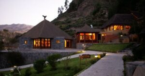 🌄 Colca Canyon Eco Retreat – Sustainable Glamping In The Andes 1 lodge with side walk with buildings and shrubs with mountain sat a canyon.