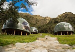 Several glamping domes on structures with trees and mountains