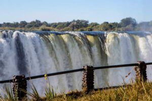Large waterfalls in Africa and a railing with trees.