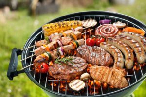 Grill roasting food at a summer campsite during outdoor adventure trip with tents and nature in the background
