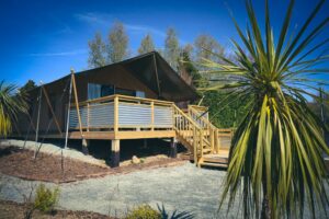 🌅 Riverside Glamping in Puerto Iguazú: Jungle Comfort by the Water 4 Glamping structure with a wooden deck surrounded by dense rainforest vegetation