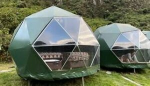Nature Domes In Lunahuaná Valley 4 Two green glamping domes with beds a person and a forest