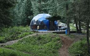 Riverfront Dome, Guapimirim – Tranquil Jungle Retreat By The River 3 Glamping dome on a platform with table and chairs in a forest.