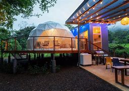Glamping dome with a porch and table and chairs with a grill and another room.
