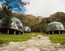 Several glamping domes on a hill on platforms in a forest.