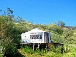 🏝 Luxury Yurt, Santa Teresa – Bohemian Comfort In Rio’s Artsy Beach District 3 Luxury Yurt on a platform on a hill with trees and vegetation.